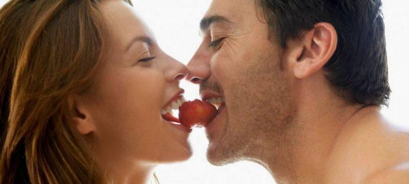 man and woman eating strawberry